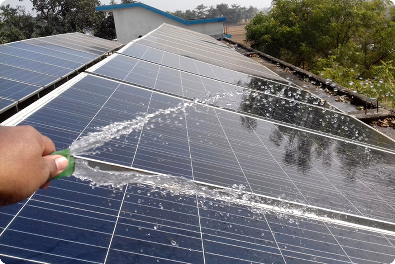 Hand spraying water on solar panel
